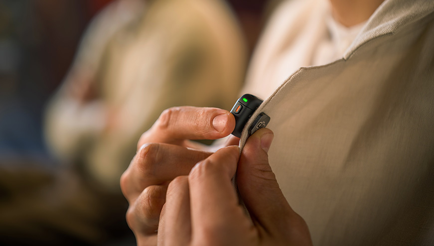 System mikrofonów bezprzewodowych DJI Mic 3 2 TX + 2 RX + Etui ładujące czarny grafika przedstawia osobę przypinającą mikrofon do koszuli